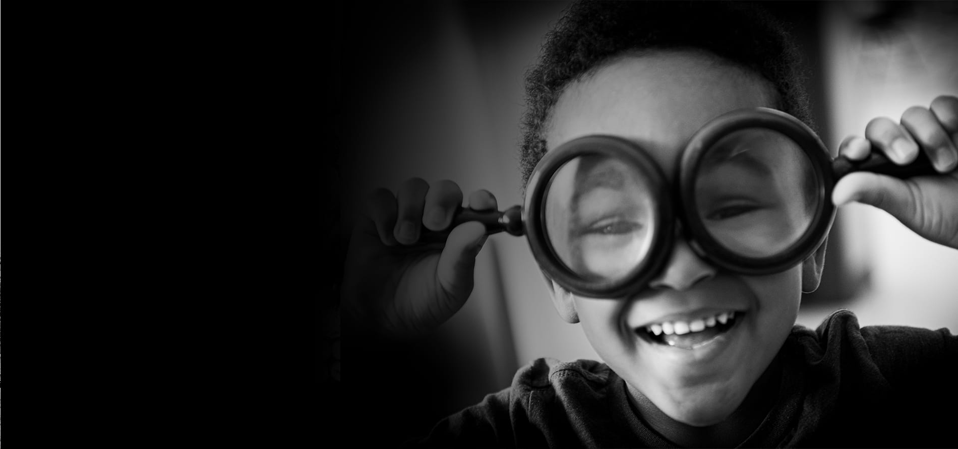 A little boy plays around with magnify glasses